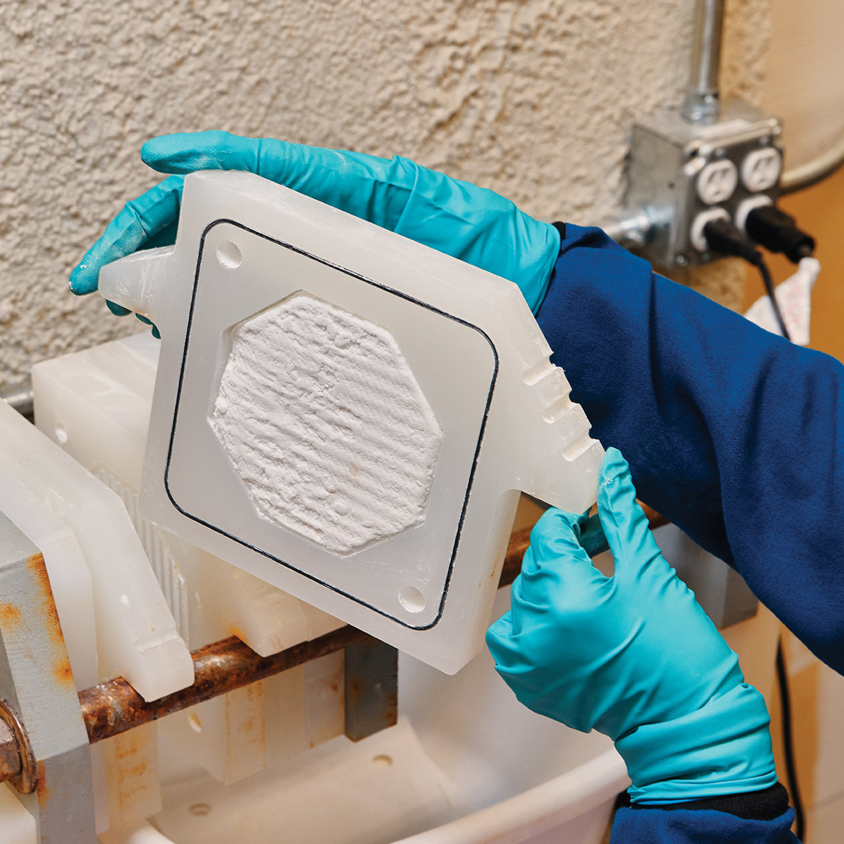 closeup of the workers hands holding cement in an octagonal plastic mold