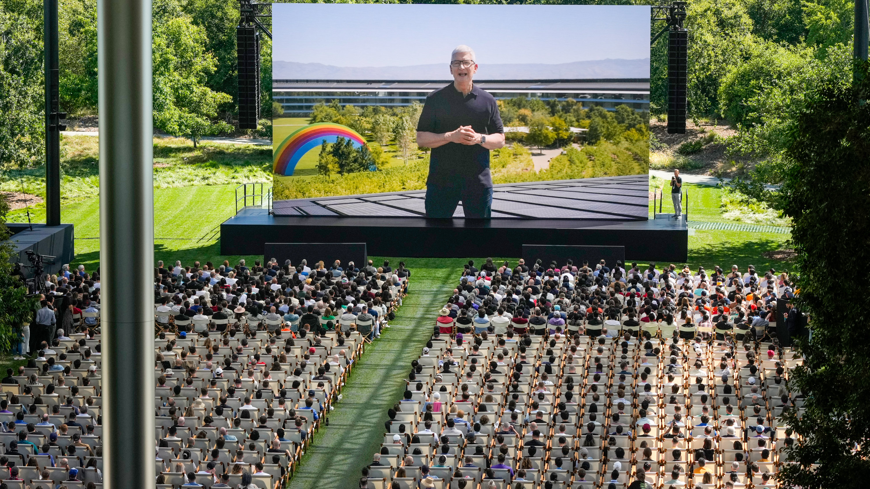 A large outdoor screen shows Apple CEO Tim Cook during an announcement of new products on the Apple campus